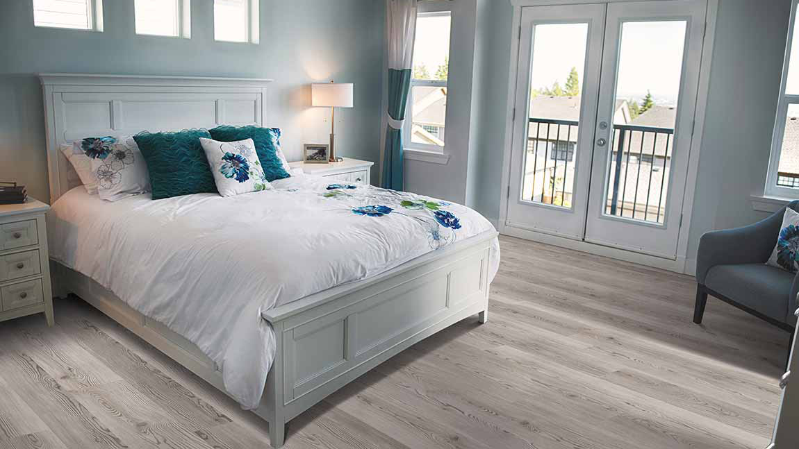 Luxury Vinyl flooring within a bedroom setting with a while bed frame and large glass doors